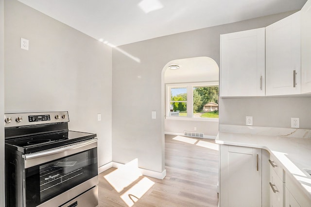 kitchen with stainless steel electric range oven, light hardwood / wood-style flooring, and white cabinets