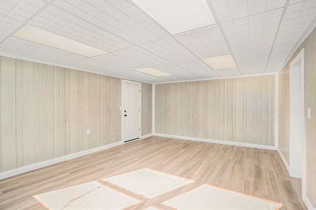 empty room with light wood-type flooring and wooden walls