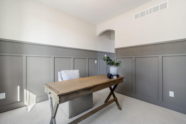 office space with a decorative wall, light carpet, visible vents, and wainscoting