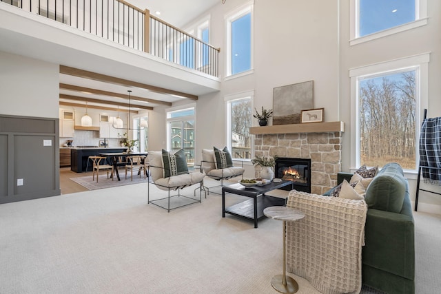 living room with light carpet, a high ceiling, beam ceiling, and a fireplace