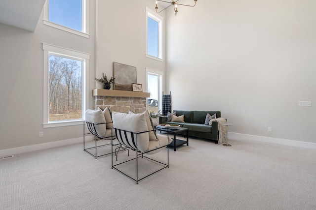 carpeted living room with visible vents, a high ceiling, a fireplace, and baseboards