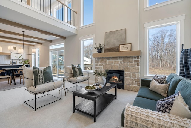 living room with beam ceiling, a fireplace, light carpet, and a towering ceiling