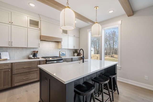 kitchen with gas stove, premium range hood, a sink, beamed ceiling, and tasteful backsplash