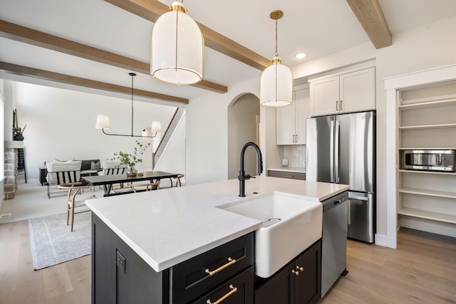 kitchen with light countertops, decorative light fixtures, appliances with stainless steel finishes, and a sink