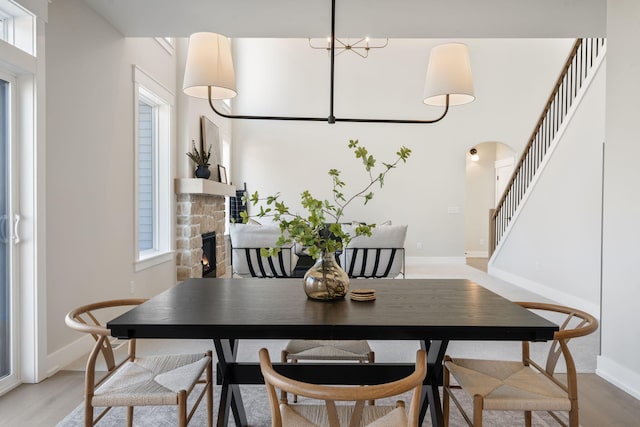 dining room featuring a fireplace, stairs, light wood-type flooring, and baseboards