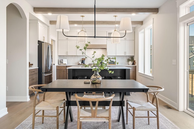 dining space with visible vents, light wood-style flooring, beamed ceiling, and baseboards