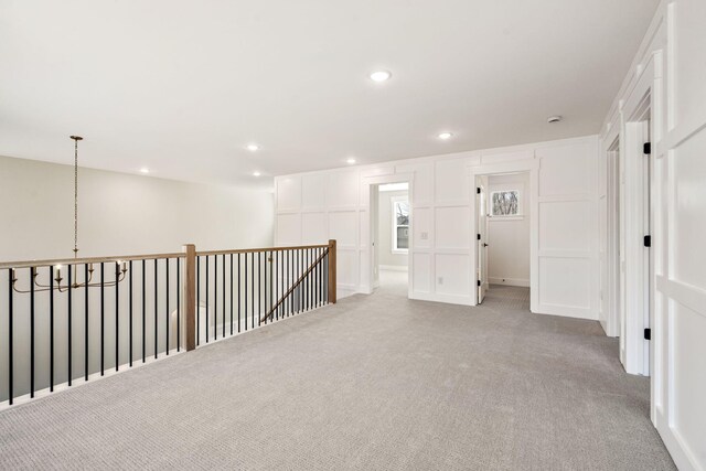 spare room featuring an inviting chandelier, recessed lighting, and light carpet