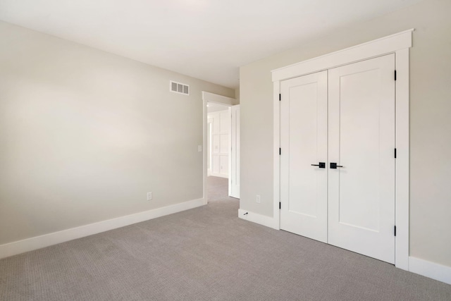 unfurnished bedroom with carpet flooring, baseboards, visible vents, and a closet