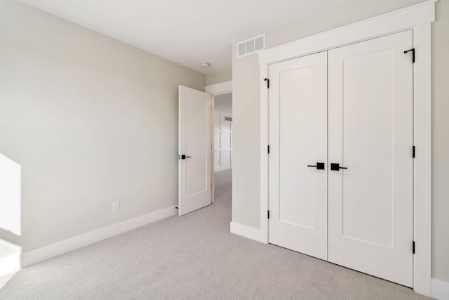 unfurnished bedroom featuring visible vents, baseboards, light colored carpet, and a closet