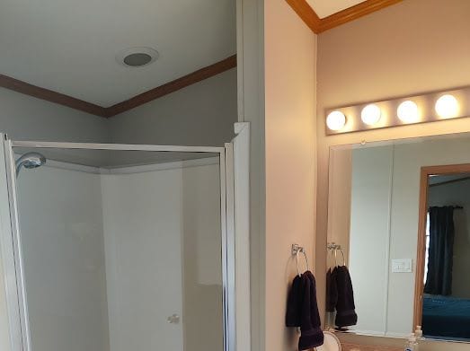 bathroom with a shower and ornamental molding