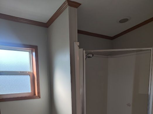 bathroom with a shower, crown molding, and lofted ceiling