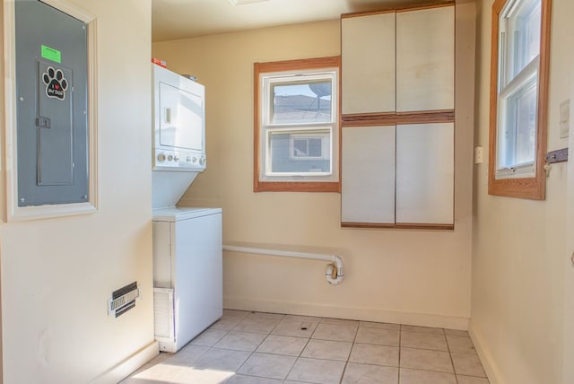 laundry area with light tile patterned floors, electric panel, and stacked washer and dryer