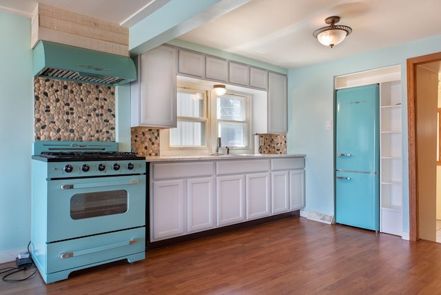 kitchen with premium range hood, dark wood-type flooring, white cabinets, decorative backsplash, and white range oven