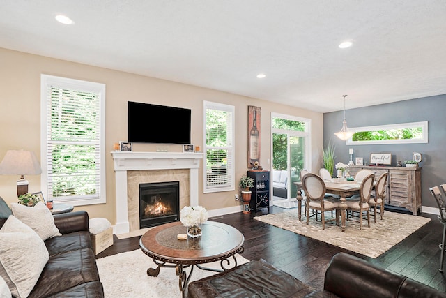 living room with a tile fireplace and dark wood-type flooring