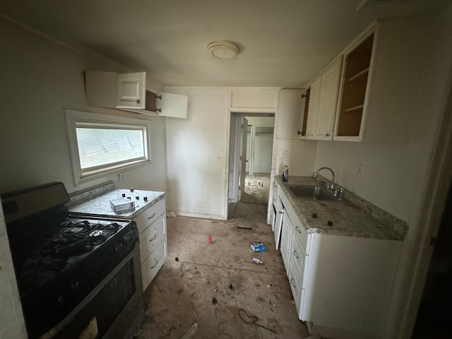 kitchen with black electric range oven, light stone countertops, white cabinetry, and sink