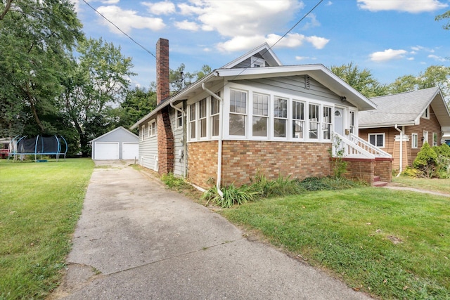 view of front facade featuring a sunroom, an outbuilding, a garage, a front yard, and a trampoline