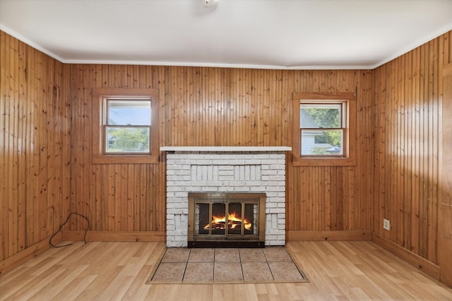 unfurnished living room featuring a fireplace, light wood-type flooring, a wealth of natural light, and ornamental molding