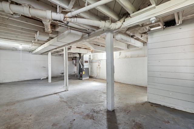 basement with heating unit and wood walls