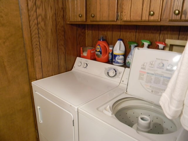 laundry room featuring cabinets, washer and clothes dryer, and wood walls