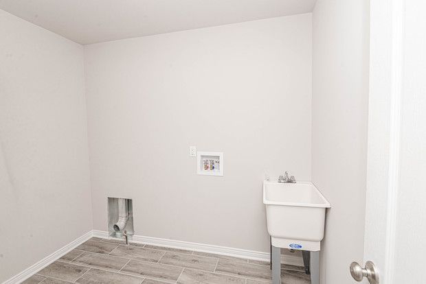 laundry room with sink, hookup for a washing machine, and light wood-type flooring