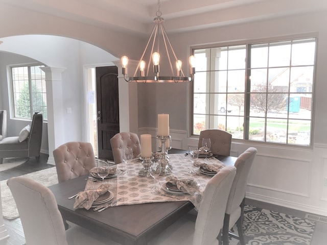 dining area featuring ornate columns, a healthy amount of sunlight, and a notable chandelier