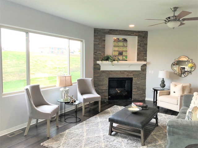 living room featuring ceiling fan, a stone fireplace, and wood-type flooring