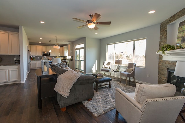 living room with ceiling fan, a fireplace, and dark hardwood / wood-style floors