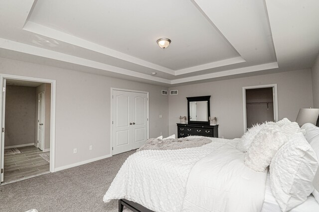 bedroom with carpet, ensuite bathroom, and a raised ceiling