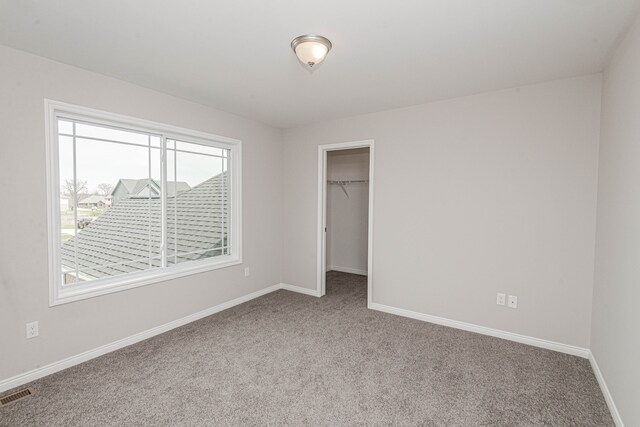 unfurnished bedroom featuring light colored carpet, a spacious closet, and a closet