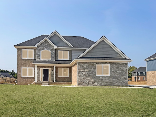 craftsman house with stone siding, a shingled roof, and a front lawn