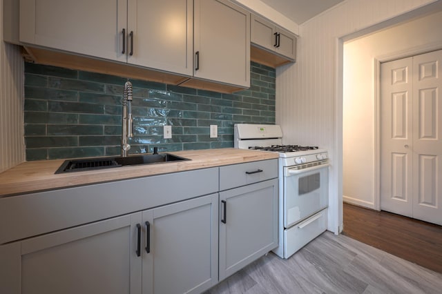 kitchen with wooden counters, white gas range oven, gray cabinetry, sink, and light hardwood / wood-style floors