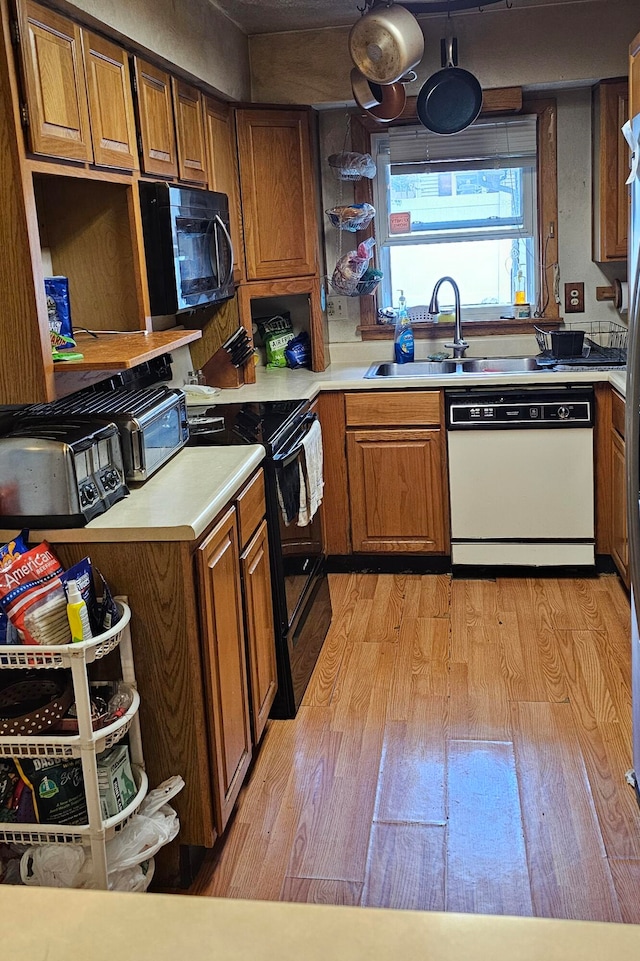 kitchen with black appliances, light hardwood / wood-style floors, and sink