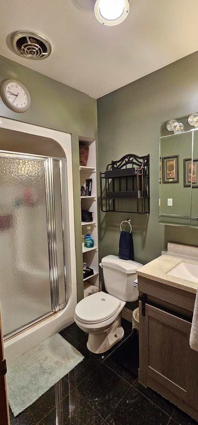 bathroom with tile patterned floors, vanity, toilet, and a shower with door