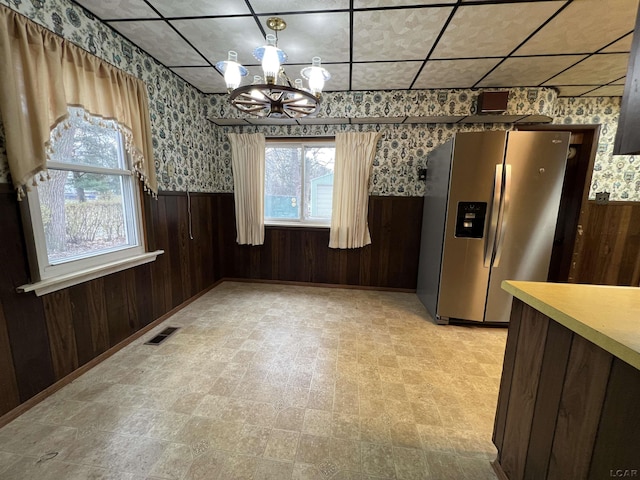 unfurnished dining area with wood walls and a chandelier