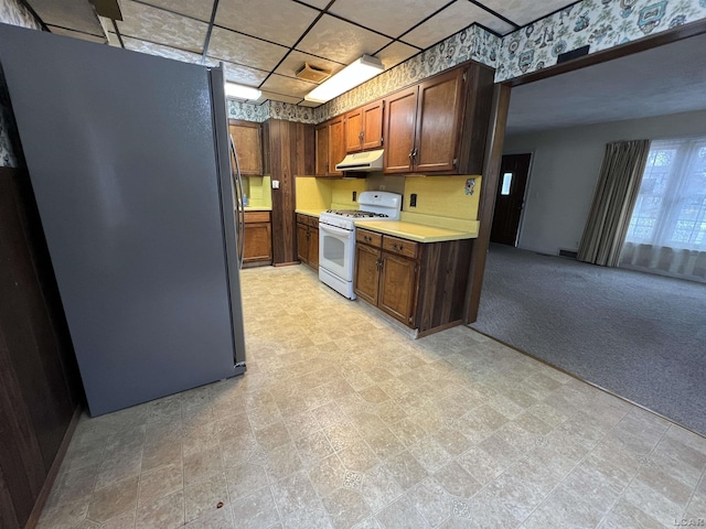 kitchen featuring light carpet, stainless steel fridge, and white range with gas cooktop