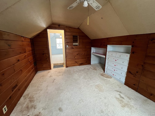 bonus room with ceiling fan, carpet floors, wooden walls, and lofted ceiling