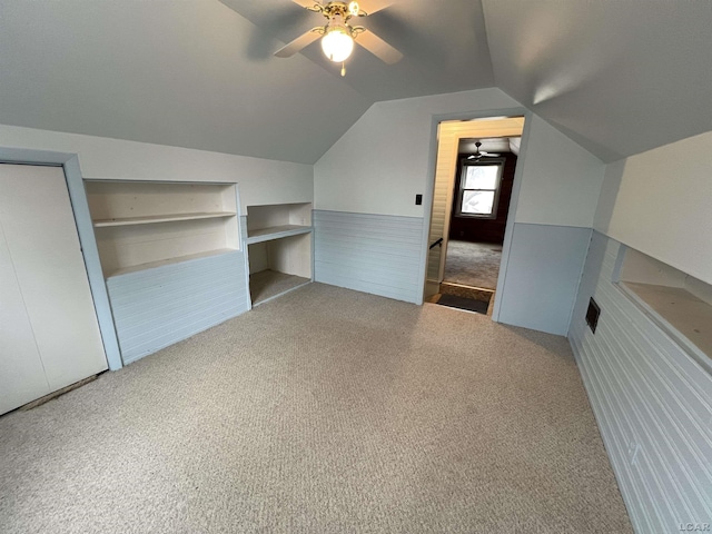 additional living space with vaulted ceiling, ceiling fan, carpet floors, and built in shelves