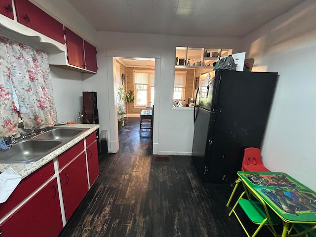 kitchen with black refrigerator, dark hardwood / wood-style flooring, and sink