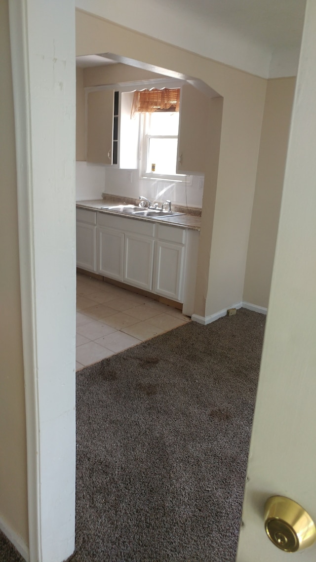 kitchen featuring white cabinets, sink, and light carpet