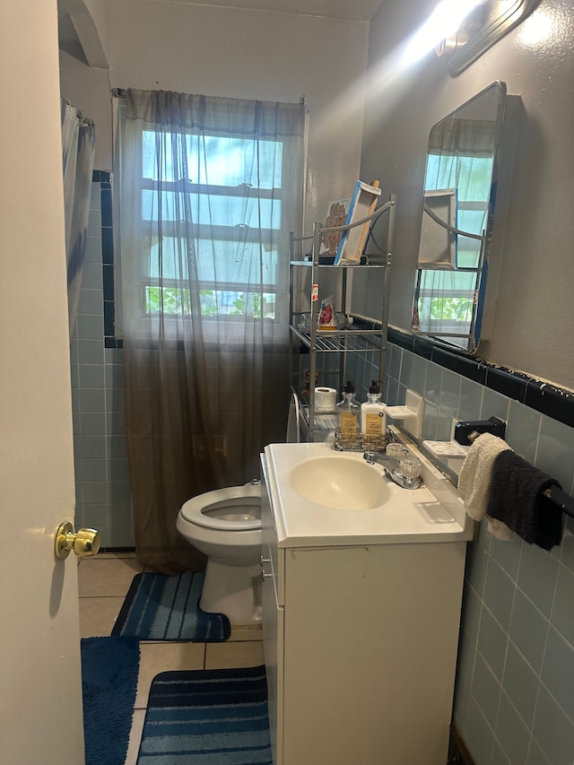 bathroom featuring tile patterned flooring, vanity, a healthy amount of sunlight, and tile walls