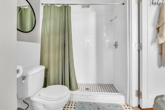 bathroom featuring tile patterned floors, a shower with curtain, tile walls, and toilet