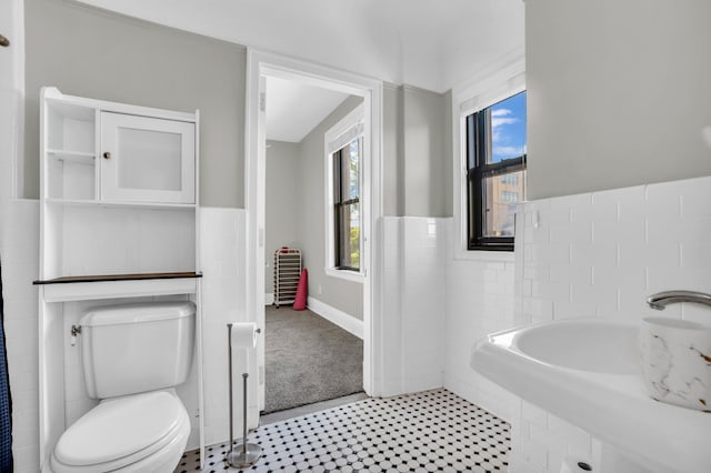 bathroom featuring toilet and tile walls