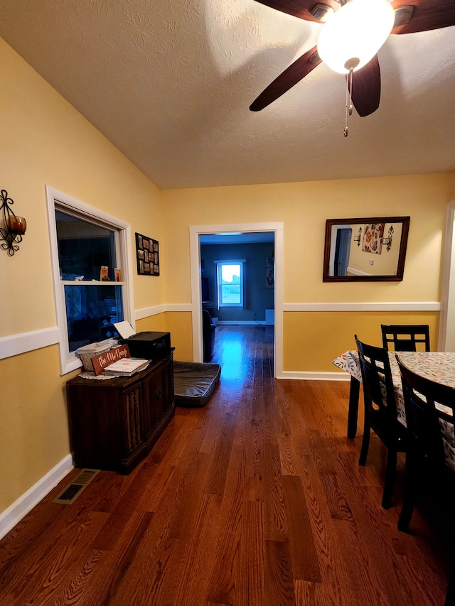 dining space with a textured ceiling, ceiling fan, and dark wood-type flooring