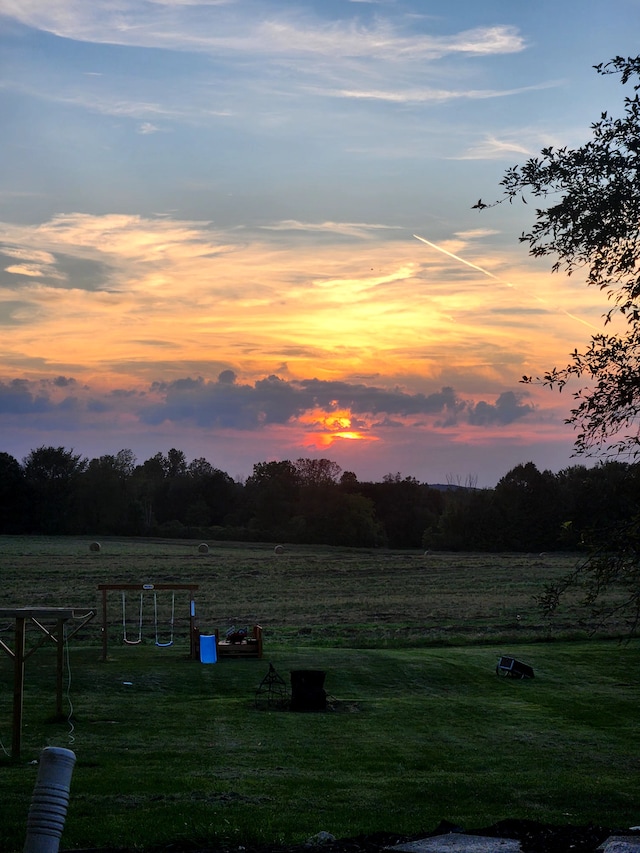 yard at dusk featuring a rural view