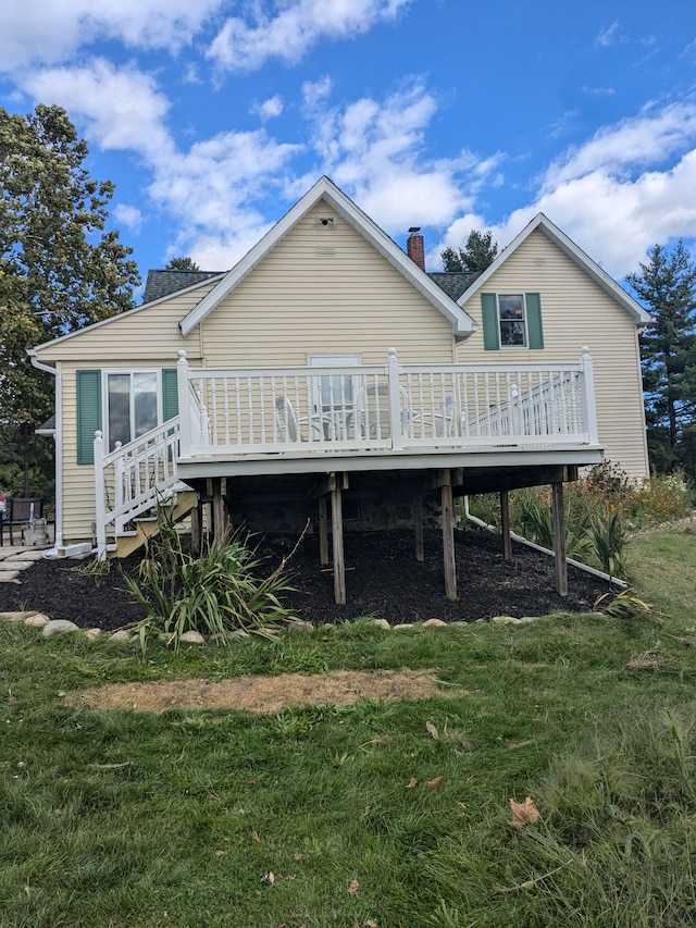 back of house featuring a lawn and a wooden deck