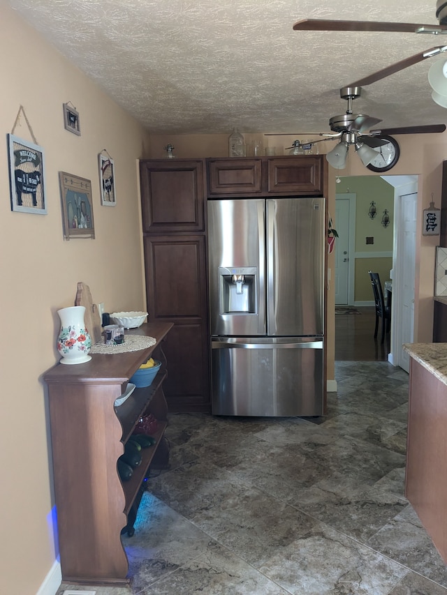 kitchen featuring stainless steel fridge, a textured ceiling, dark brown cabinetry, and ceiling fan