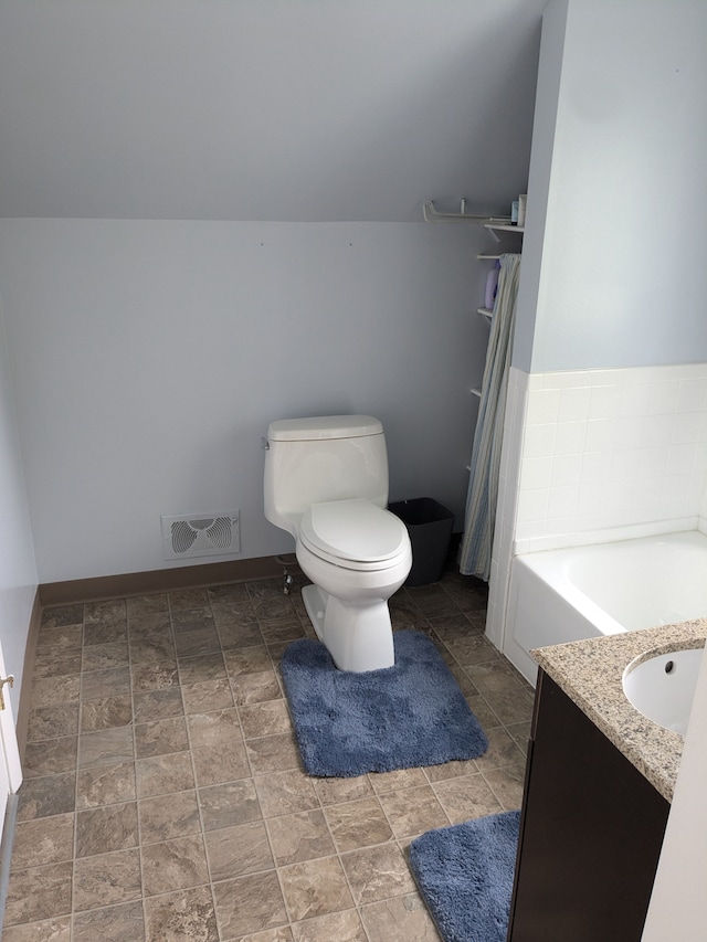 bathroom featuring a bathing tub, vanity, toilet, and vaulted ceiling