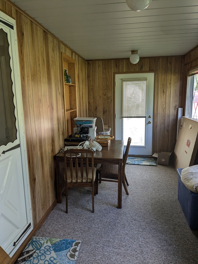 carpeted dining room with wooden walls