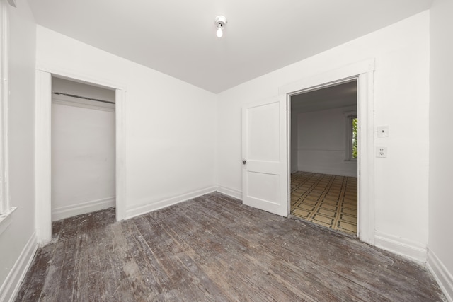 unfurnished bedroom with dark hardwood / wood-style flooring and a closet