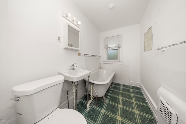 bathroom with a tub to relax in and toilet